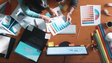 Tasarımcı yazma fikri ekrana bakarken proje yöneticisinin üst görünümü. Akıllı iş adamlarını kapat ve tasarımcı palete bakarken logo tasarımı fikrini açıkla. Sempozyum.