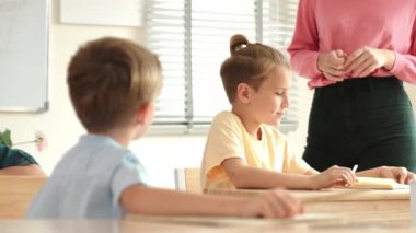 Beyaz bir çocuk ödevlerini yaparken ve açıklama dinlerken güzel bir öğretmen sınavı açıklıyor. Sınıfta not alırken ya da kağıda cevap yazarken öğretmenine bakan sevimli bir çocuk. Pedagoji.