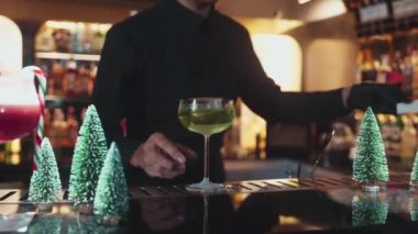 Barmen tarafından sunulan karamelize edilmiş turunçgil dilimli Midori Sour kokteyli, akıllı misafir konuşmacısına kokteyl ve şeker kamışı Noel temalı kokteyl ikram ediliyor. Vinosity.