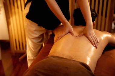 Beyaz erkek müşteri stres önleyici spa masajının keyfini çıkarıyor ve lüks otel ya da oteldeki ortam kaplıcalarında sıcak mum ışığında güzellik teniyle eğleniyor. Sessiz.