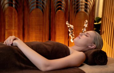Beyaz kadın müşteri stres önleyici spa masajının keyfini çıkarıyor ve lüks otel ya da otelde sıcak mum ışığında güzellik teniyle eğleniyor. Sessiz.