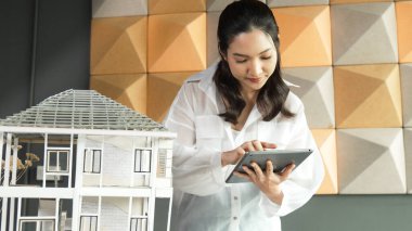 Tablet kontrol evi modelini kullanan güzel bir proje yöneticisi. Mimar mühendisinin portresi tabletteki veri analizini kullanarak bina inşaatını denetliyor. İş inşaat konsepti. Yönlendirici.