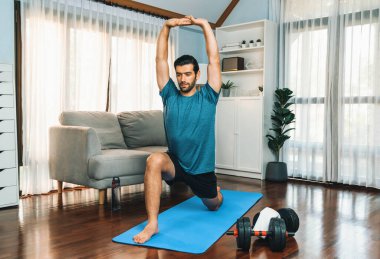 Atletik ve sporcu adam, evdeki fiziğe ve sağlıklı spor yaşam tarzına uygun vücut egzersizlerinden önce ısınıyor ve esniyor. Gaiety ev egzersizi antrenman konsepti.