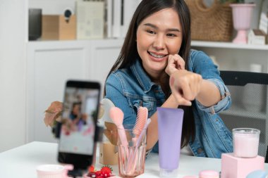 Genç, güzel Asyalı kozmetik makyaj ruju matte pastel rengini modern odadaki sosyal medyada kol testi tanıtımında en çok satanlar listesinde gösteriyor. Taktik.