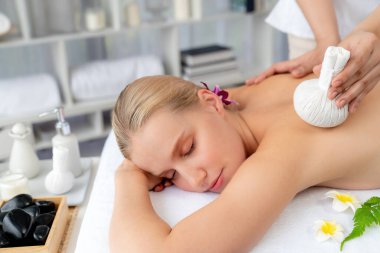 Sıcak bitkisel top spa masaj vücut tedavisi, masör kadın vücuduna nazikçe şifalı bitki torbası bastırıyor. Aromaterapi dinlenme sükuneti ve sükuneti kaplıca salonundaki atmosferi aydınlatıyor. Sessiz.