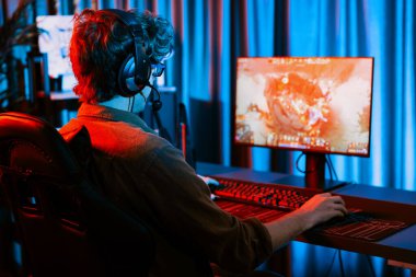 Savaş arenasında çoklu oyunlar takımıyla Moba 'da savaşan genç oyun flamasının sunucu kanalı, neon dijital ışık modern odasındaki arka görüntü ile bilgisayar monitöründe kulaklık takıyor. Toplayıcı.