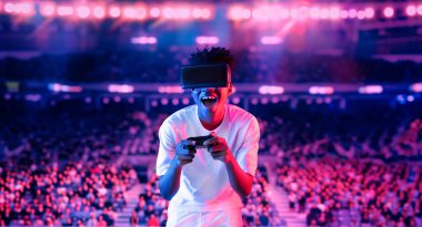 Yetişkinlerin elinde joystickle VR gözlükleri varken stadyumda arka planda bulanık oyunlar oynamaktan zevk alıyorlar. Afrikalı adam kontrol etmeyi ve artırılmış gerçeklik teknolojisini kullanmayı seviyor. Yaratıcılık.