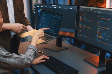 Modern ofisteki neon ışık odasında bilgi ağını gösteren dizüstü bilgisayarla iki ekranda veri çalıştıran akıllı web sitesi geliştirme kodlayıcı sistemini tartışan IT geliştiricilerinin ciddiyeti. İnfobahn.