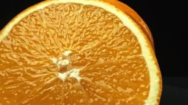 Portakal diliminin bir makrografi görüntüsü, parlak, izole edilmiş bir arkaplan üzerine yerleştirilmiş, narenciye cazibesinin görsel bir başyapıtı olarak gözler önüne seriliyor. Siyah arkaplanlı bir dilim portakal. Geliştirilebilir.