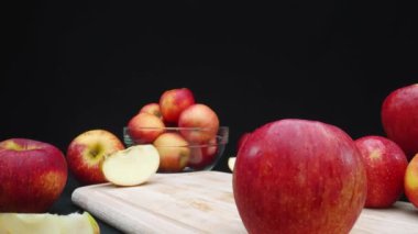 Elmaların makrografisi çeşitli şekillerde sergilenir: bütün, dilimlenmiş ve siyah arka planlı cam bir kase içinde. Her yakın çekim kesme tahtasındaki elmaların kırmızı renklerini yakalar. Geliştirilebilir.