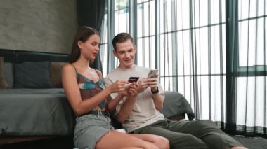 Genç çift, kredi kartıyla ödemek için internet üzerinden ödeme uygulaması ve dijital cüzdan kullanarak yatak odasında oturuyor. Mobil internet üzerinden alışveriş ve modern alımlar. Düzenle