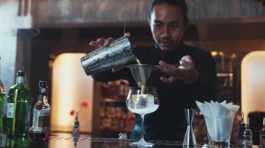 Asyalı barmen, alkollü likör ve şuruplu kokteyl bardağına kattığı her şeyi süzgeçle temizliyor. Lüks gece kulübünde gece hayatı karışımı sergileniyor. Vinosity.