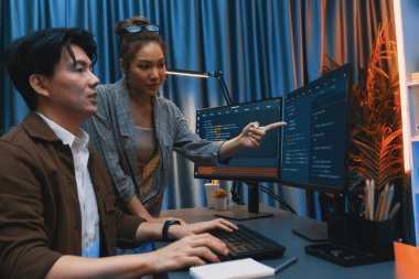 Bilgi teknolojisi geliştiricileri modern ofisteki neon ışık odasında verileri çevrimiçi olarak çalıştıran akıllı web sitesi geliştirme kodlayıcı sistemine işaret ediyorlar. İnfobahn.