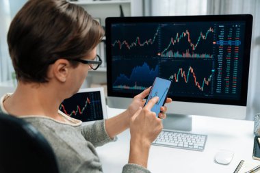 Akıllı borsa yatırımcıları ekranda akıllı telefon ile piyasa borsasını işaret ederek dizüstü bilgisayarın yanı sıra en yüksek dinamik yatırım oranını göstererek, modern işyerindeki veri planlamasına odaklanıyorlar. Bireysel.