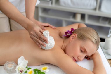 Sıcak bitkisel top spa masaj vücut tedavisi, masör kadın vücuduna nazikçe şifalı bitki torbası bastırıyor. Aromaterapi dinlenme sükuneti ve sükuneti kaplıca salonundaki atmosferi aydınlatıyor. Sessiz.