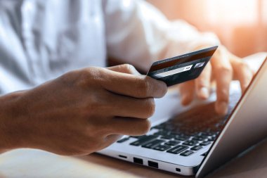 Genç adam, laptop bilgisayar başvurusu ya da web sitesinde online alışveriş yapmak için kredi kartı kullanıyor. E-ticaret ve online alışveriş konsepti. uds