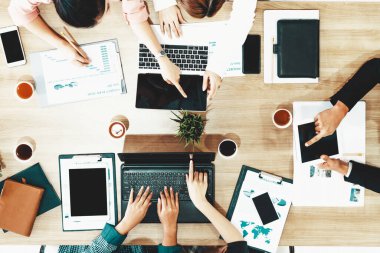 Modern ofisteki iş adamları ve iş kadınlarıyla grup toplantısındaki iş adamlarının en üst düzey görüşü, masada dizüstü bilgisayar, kahve ve belge ile. Kurumsal şirketler uds