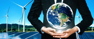 Alternatif enerji ile sürdürülebilirlik gelişimi kavramı. Çevre dostu rüzgar türbini çiftliği ve arka planda yeşil yenilenebilir enerji olan gezegenle insan eli ilgilenir. uds