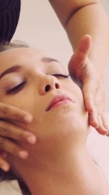 Lüks bir spa merkezinde masaj terapisti tarafından yüz masajı ve spa tedavisi için kaplıcaya uzanmış rahat bir kadın. Sağlık, stres atma ve gençleştirme kavramı.