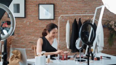 Kadın nüfuzlu kişi canlı yayın yapan video görüntülerini sosyal medya ya da blog üzerinden gözden geçiriyor. Kozmetik stüdyosu ışıklandırmalı mutlu genç kız çevrimiçi pazarlama oturumu yayını için..