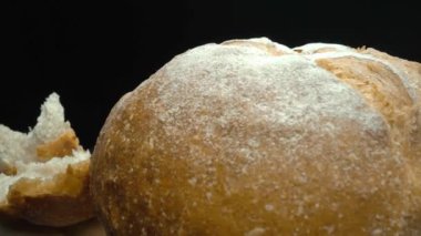 Koyu arkaplanda yırtık taze ekmek parçalarını yakın plan çek. Tahta tepsiye konmuş Fres ekmeklerinin makro fotoğrafları. Yakınlaştır ve kamera hareketini döndür. Gurme ve fırın konsepti. Pabulum.