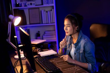 Sunucu kanalı Asyalı etkileyicisi canlı yayında konuşuyor. Sosyal medyada kulaklık takıyor, bilgisayar kaydı yapıyor, dinleyicileri selamlıyor ve Neon Modern Stüdyoları 'nda online olarak koçluk yapıyor. Taktik.