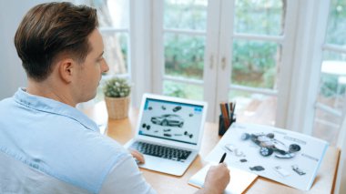 Car design engineer analyze car prototype for automobile business at home office. Automotive engineering designer carefully analyze, finding flaws and improvement for car design with laptop Synchronos clipart