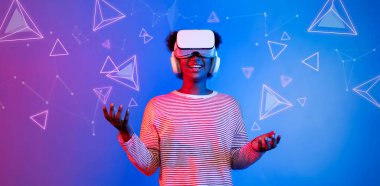 VR gözlüklü Afrikalı kız mavi ve pembe arka planda duruyor ve yüzen geometrik şekle bakıyor. Heyecanlı insan görsel gerçeklik dünyasına giriyor. Teknoloji yeniliği. Yaratıcılık.