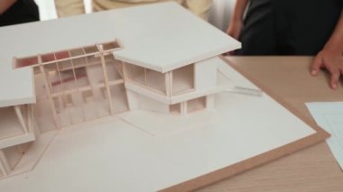 Mimari ekipman kullanarak yavaş çekim ev tasarımcısı bir plan çizerken, iç mimari tasarımcı da müşterilerin talebine göre renk örneklerinden uygun renkler seçiyor. Değiştirilmiş