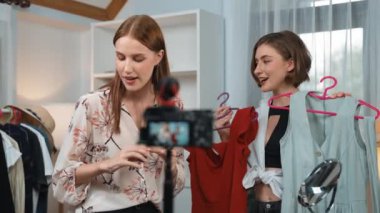 İki kadın nüfuzlu kişi canlı yayın yapan video klip eleştirisi kıyafetlerini sosyal medyada ya da blogda yayınlıyor. Stüdyo ışıklandırmalı mutlu genç kız çevrimiçi pazarlama oturumu yayını için..