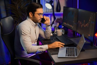 Tüccar akıllı işadamı komisyoncuyu ya da ortağını arıyor, modern evde kârlı bir finans teknolojisi olan neon aydınlatma ofisindeki bilgisayardaki dinamik borsa yatırımlarını analiz ediyor. Tahmin et..