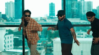 Bir grup enerjik hippi pencere kırıcının yanında dans ediyor. Kameraya bakarken enerjik dansçı pozu. Açık hava sporu 2024. Serbest stil dansı. Mavi arka plan. Hiphop.