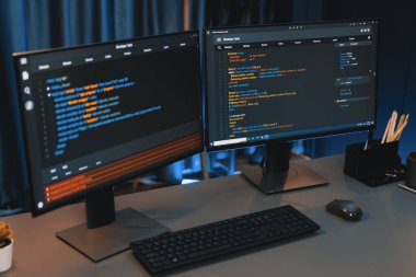 Bilgisayardaki programlama kodu masaüstü çalışma masasındaki iki ekranda akıllı web sitesi geliştirme kodlayıcı sisteminin neon ışık odasında veri teknolojisi çalıştırdığını gösteriyor. İnfobahn.