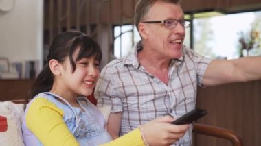 Büyükbaba ve torun birlikte TV 'de ilginç bir eğlence medyası izliyorlar. Eski üst düzey kullanım teknolojisi, genç nesil çapraz nesil ile iletişim kurarak aile bağlarını güçlendiriyor. Uyumsuzluk.