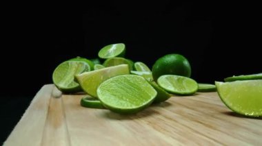 Yakın plan, canlı bir dilim taze kireç kırsal bir ahşap kesme tahtasının üzerinde duruyor. Tazelik ve canlılık yayıyor. Kesme tahtasına konmuş yeşil limon diliminin yarı saydam zarları. Geliştirilebilir.