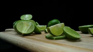 Yakın plan, canlı bir dilim taze kireç kırsal bir ahşap kesme tahtasının üzerinde duruyor. Tazelik ve canlılık yayıyor. Kesme tahtasına konmuş yeşil limon diliminin yarı saydam zarları. Geliştirilebilir.