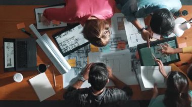 Yöneticinin proje planı yazması ve toplantıda oturması. Bilgisayarlı ve teçhizatlı ev inşaatı hakkında planlar yapan ve paylaşan iş adamlarının havadan görüşü. Sempozyum.