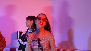 Çok kültürlü bir arkadaş birlikte dans ediyor ve hiphop müziği eşliğinde restoranda ya da kafede pembe neon ışıklı duruyor. Profesyonel sokak dansçıları grubu enerjik hareketler sergiliyor. Mutluluk.