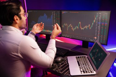 Akıllı tüccar işadamı, karanlık oda gecesinde neon ışıklı ofisteki arama pazarında yüksek kârla ekranda bilgisayar ve bilgisayar üzerinde dinamik borsa yatırımları üzerinde yoğunlaşıyor. Tahmin et..