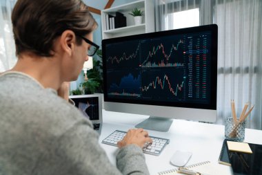 Bilgisayar ve dizüstü bilgisayarı kullanarak, çalışma masasındaki dinamik artırılmış borsa grafiğinin en yüksek kar değerini araştıran bir tüccar, modern ofisteki ekrandaki döviz kuru değerini analiz ediyor. Bireysel.