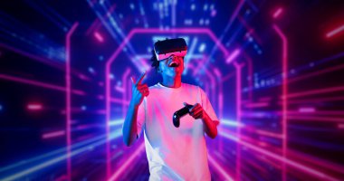 Neon soyut arka planda oyun oynarken elinde joystick tutan ve VR gözlük takan bir genç. Afrikalı adam kontrol etmeyi ve artırılmış gerçeklik teknolojisini kullanmayı seviyor. Yaratıcılık.