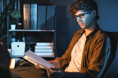 Genç işadamı, Neon Light Modern Ofis 'teki yeni proje surround çalışma masası için kağıt üzerinde tasarım düşünüyor. E-posta ile hediye göndermeden önce not defterine yeni bir iş düşünüyorum. Toplayıcı.