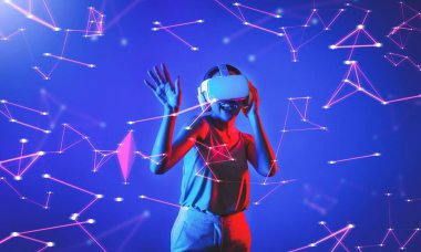 Beyaz VR kulaklık takan ve metaevreni birleştiren kolsuz tişört giyen, gelecekteki siber uzay topluluğu teknolojisi olan bir kadın siber punk neon ışığı altında el ve vücut hareketleriyle dans etmekten zevk alıyor. Halüsinasyon.