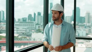 Profesyonel mühendis gökdelen manzarasına bakarken gülümsüyor. Sıradan giyinen yetenekli bir mimar, şehir manzaralı panorama penceresinin yanında dururken plan yapıyor. İzleme