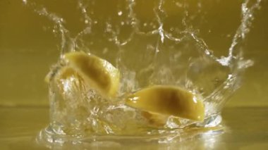 Suya düşen taze limonu kapatın ve ayrı sarı arka planda dilimlenmiş limona ayrılın. Su dalgası ve su sıçratarak. Tazelik ve canlılık kavramı. Makro. Pabulum.