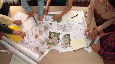 Mimari belge, ölçüm aracı ve ahşap blokların modern ofiste etrafa saçıldığı bir masa üzerinde yapı inşaatı ile ilgili mimar ve güvenlik mühendisi tartışması. Tanımlama.