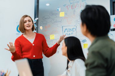 Kafkasyalı genç bir iş kadını, pazarlama stratejisini zihin haritası kullanarak sunuyor, soruları kendinden emin bir şekilde cevaplarken grafiğini çiziyor. Takım çalışması, beyin fırtınası, tartışma konsepti. Tertemiz..