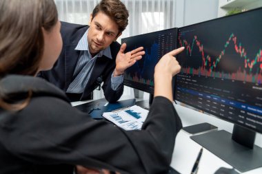 Dinamik borsada döviz kuru yatırımını tartışan iki ticaret simsarı iki bilgisayar ekranında gerçek zamanlı risk grafiği ya da modern ofisteki kar noktasını karşılaştırıyor. Varsayım.