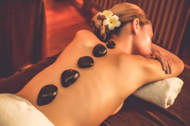 Lüks tatil köyündeki kaplıcalarda sıcak taş masajı, sıcak mum ışığı, spa bazalt taşı masajının keyfini çıkaran mutlu kadın müşteriler, rahatlatıcı bir sıcaklıkla vücudun üzerinde süzülüyorlar. Sessiz.