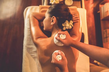 Üst görünüm sıcak bitkisel spa masaj vücut tedavisi, masör kadın vücuduna nazikçe şifalı bitki torbası bastırıyor. Spa salonundaki sıcak mum ışığında aroma terapisinin dinginliği ve sükuneti. Sessiz.